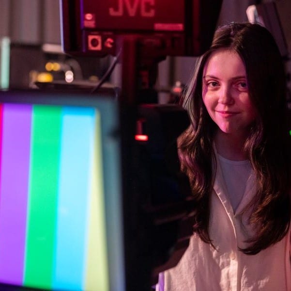 Square image of a student next to a film TV camera