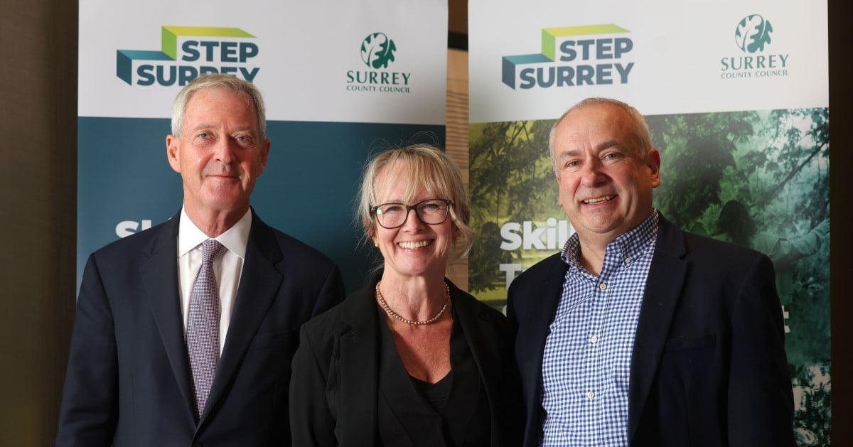 A group of professionals in suits stand in front of a STEP Surrey banner