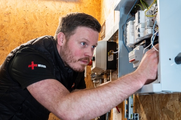 An electrician from a Surrey firm examines a fuse box in a construction classroom
