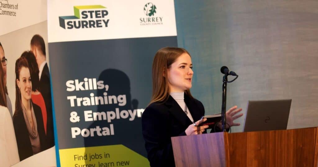 urfuture's Holly Hobbs speaks at a podium at Surrey Skills Conference. Behind her is a banner for STEP Surrey
