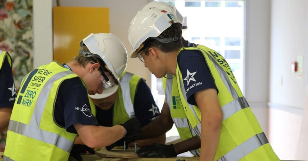 Two young people in high vis work together on a construction project