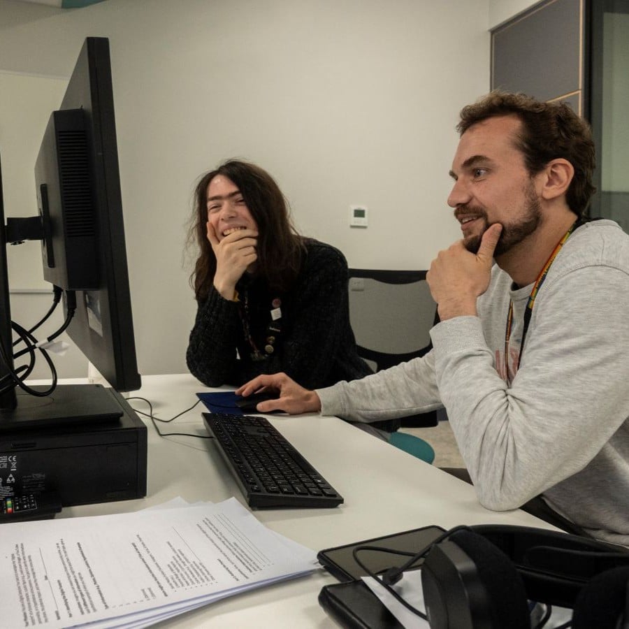 Two men sit at a computer learning in a further education college in Surrey